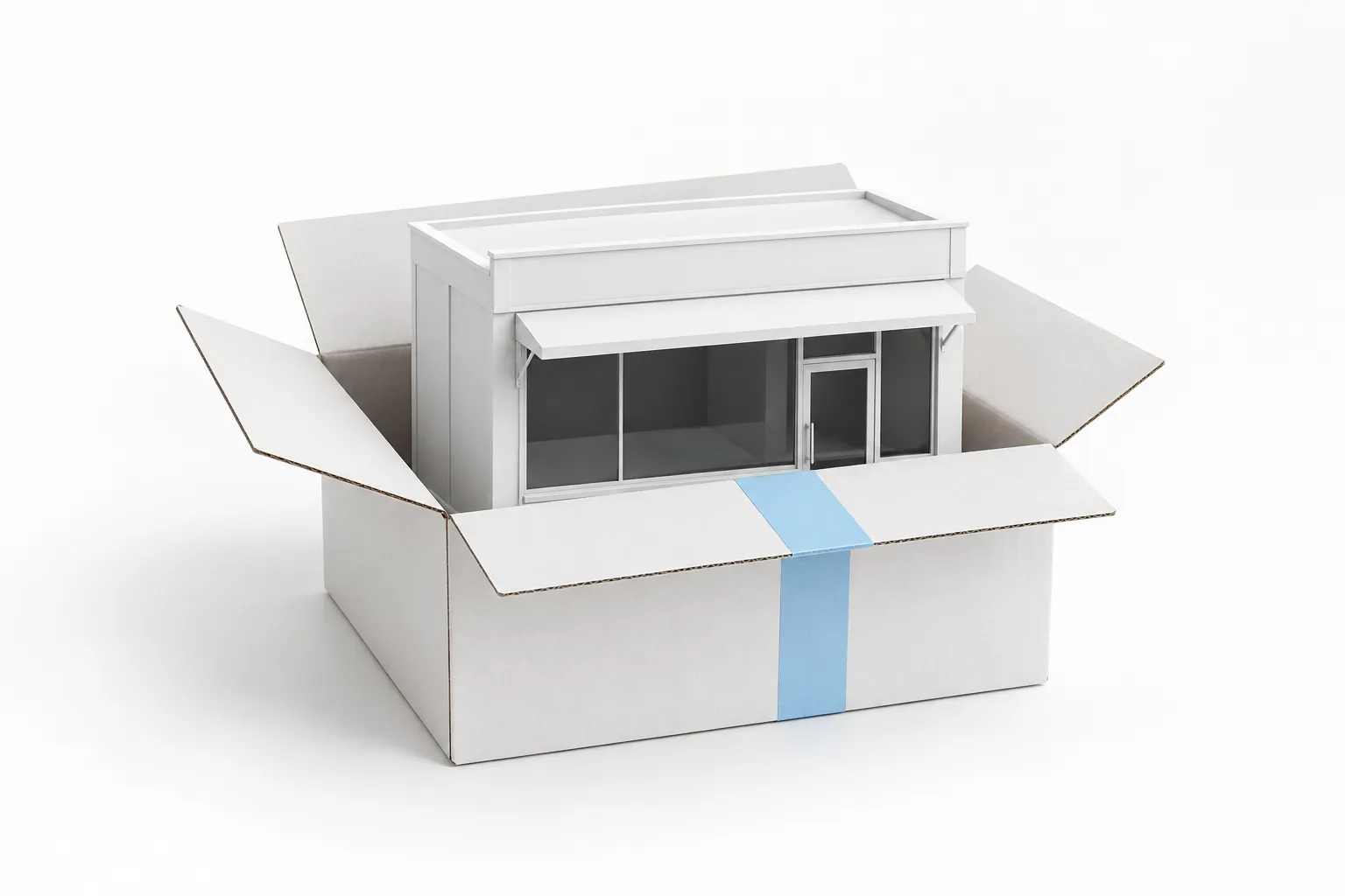 White scale model of a small shopfront packed inside an open cardboard moving box, with a strip of pale blue tape down the front.